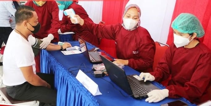 TAHAPAN : M Ilham Agung Setyawan saat mengikuti tahapan cek kesehatan berupa tekanan darah dan suhu tubuh sebelum dilakukan vaksinasi Covid-19.